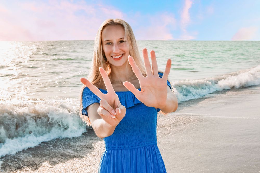 High school senior girl posing confidently outdoors during sunset senior photo session.