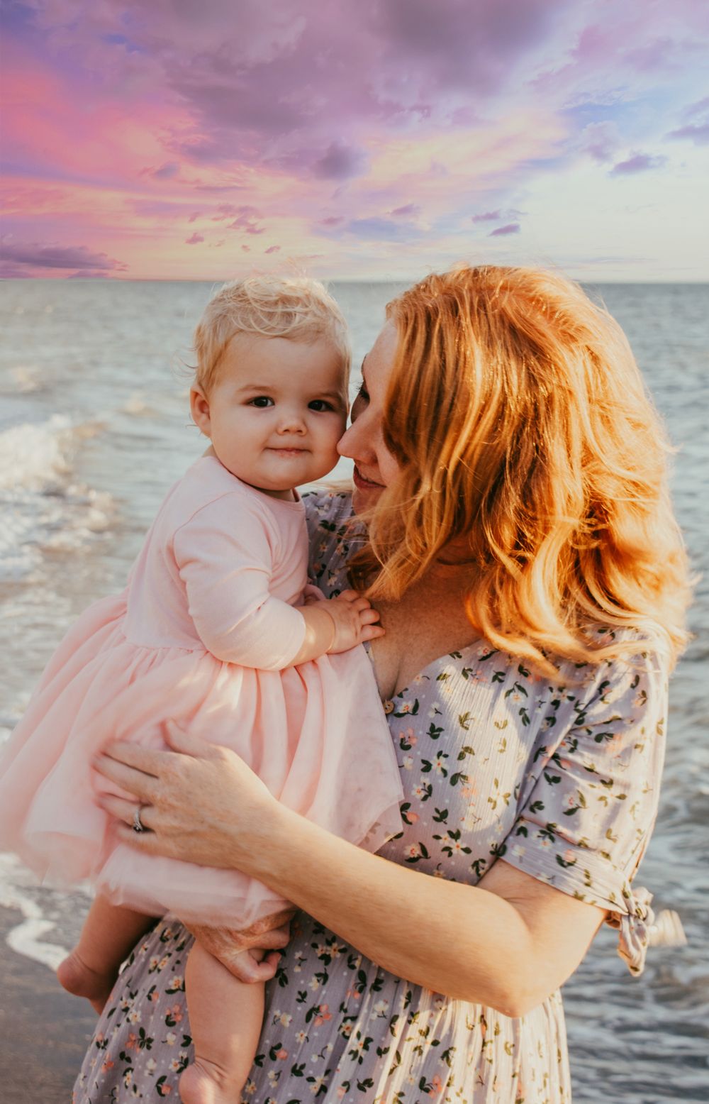 Candid moment between mom and toddler daughter on the beach during sunset family session.