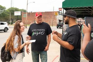 People gathered outside wearing casual attire and interacting at what appears to be a social event or gathering.
