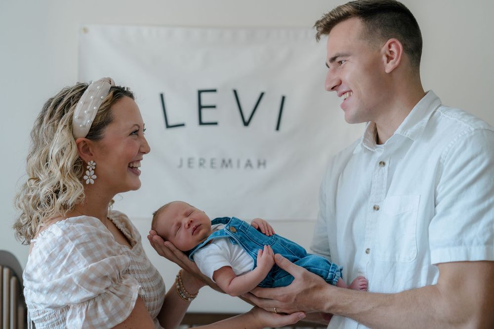 Candid photos showing loving interactions between family members with a baby in white and neutral toned settings at newborn session Stow, OH