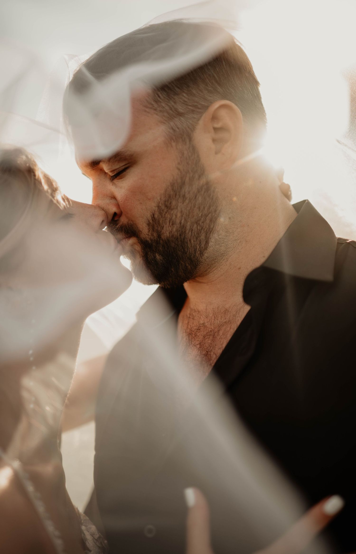 Artistic backlit portraits capture intimate moments through flowing white fabric.
