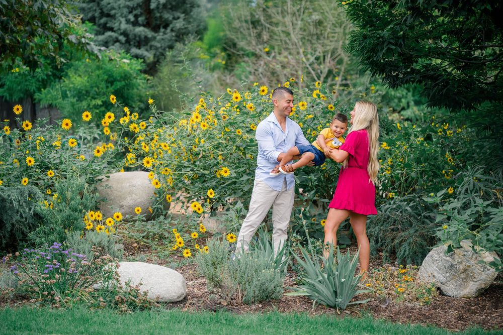 A family stands together in a garden with bright blooming yellow sunflowers in Orange County.