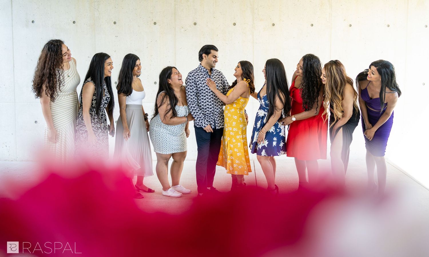 A joyful group photo session against a white wall with a pink foreground blur effect.