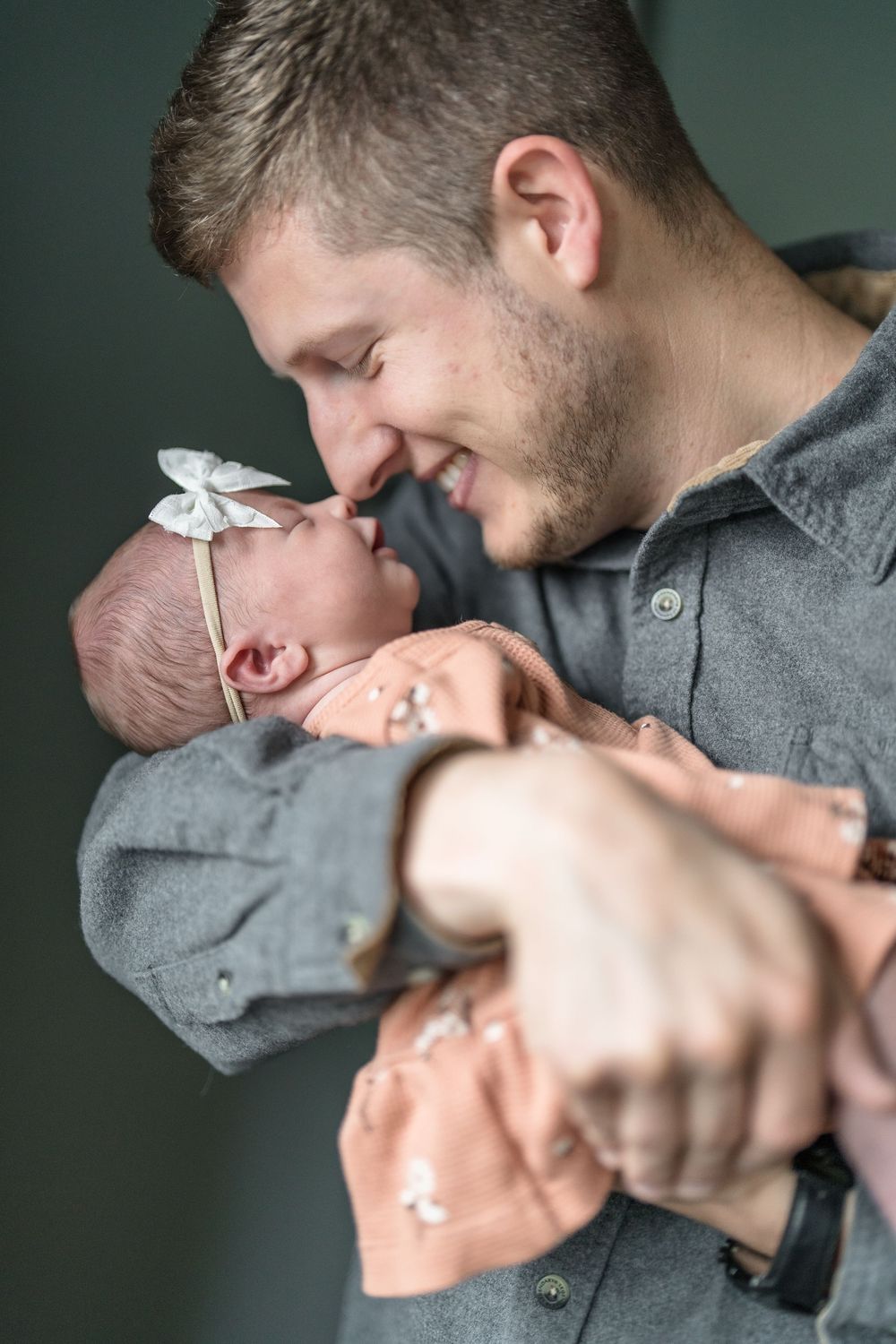 A tender moment between a parent and newborn baby wearing a white bow at this Newborn photo session in Cuyahoga Falls, Ohio.