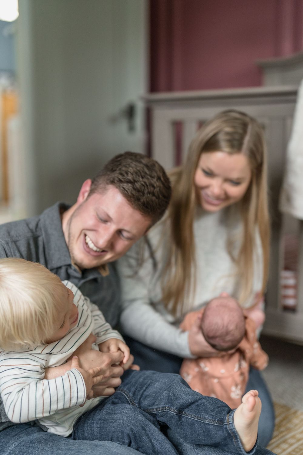 Family members playfully tickling and laughing together while lounging on floor in casual home setting in Family photo session in Ohio