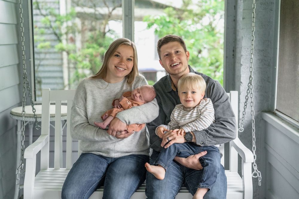 A family sitting together in a cozy gray studio setting for a professional photo shoot in Cuyahoga Falls, Ohio.