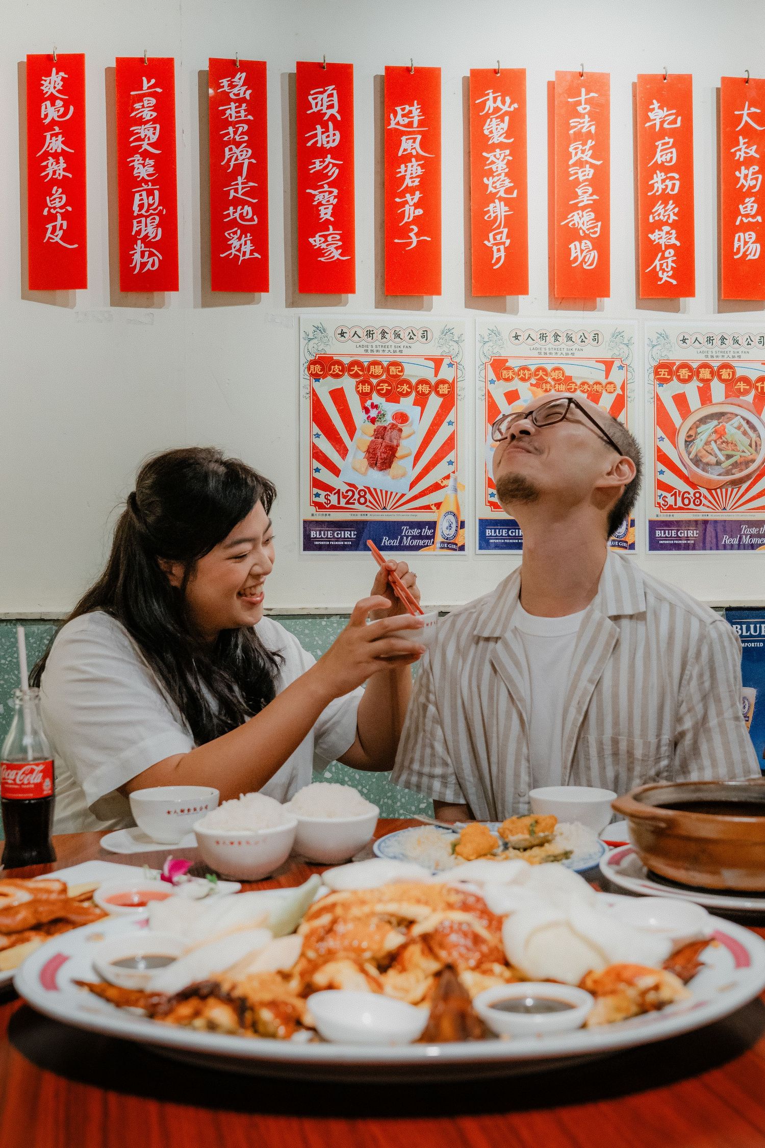 Couple dining at an Asian restaurant with decorative red banners on the wall showing Chinese calligraphy characters.