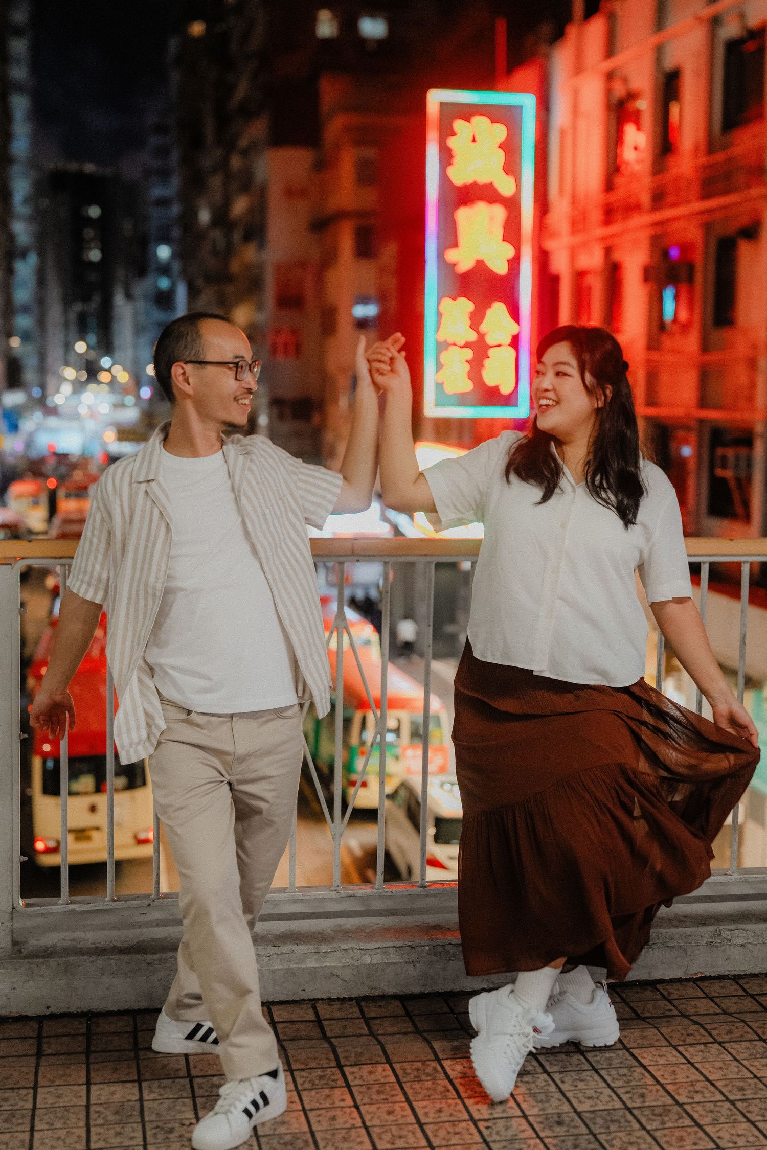 People dancing on a city street at night with bright neon signs in Hong Kong.