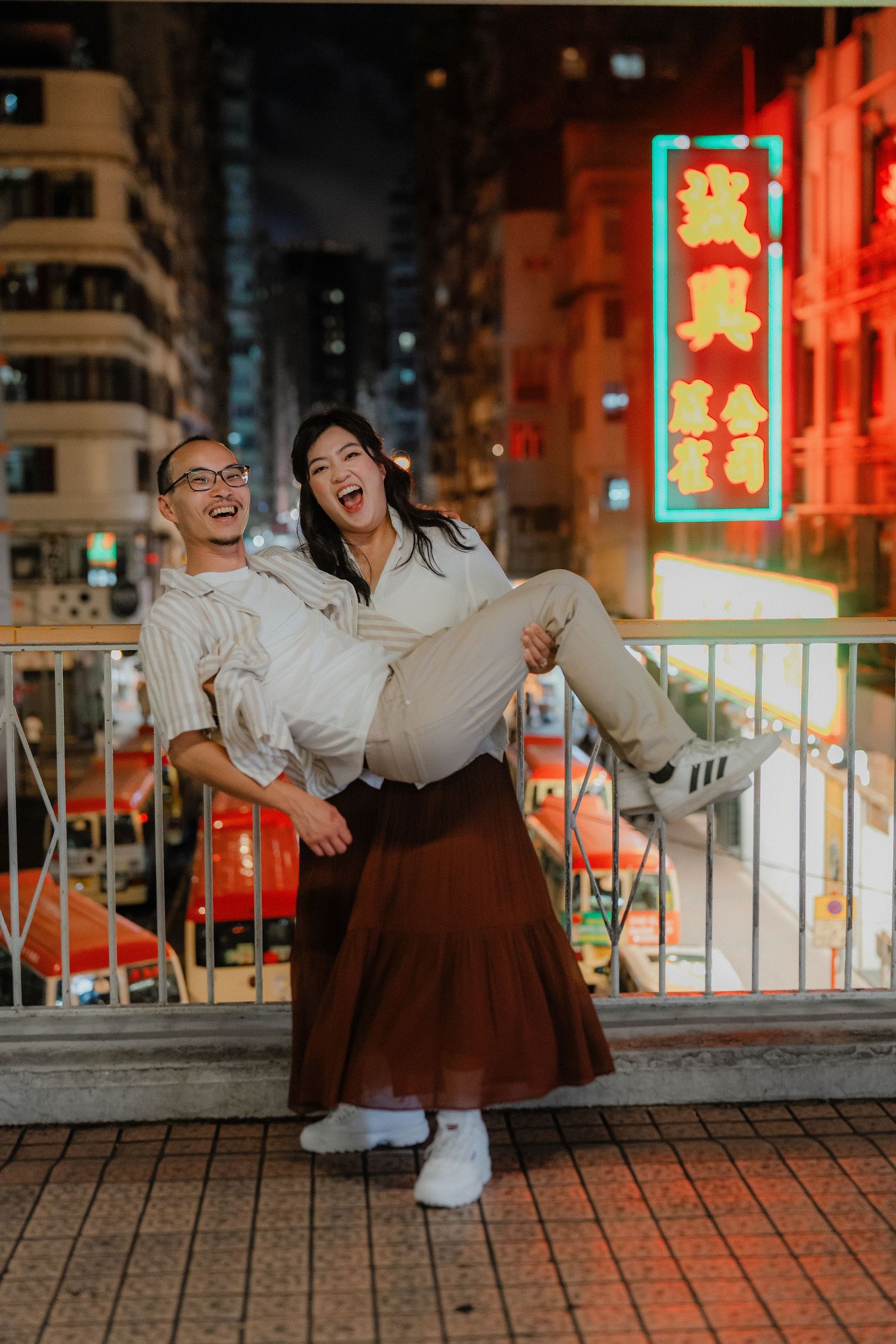 Playful moment captured against Hong Kong's neon-lit cityscape at night.