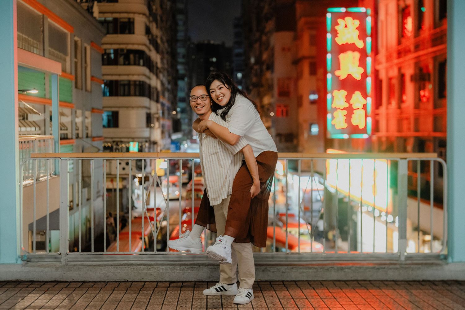 A skateboarder performs tricks in front of illuminated red lanterns and neon signs in an urban Asian setting at night.