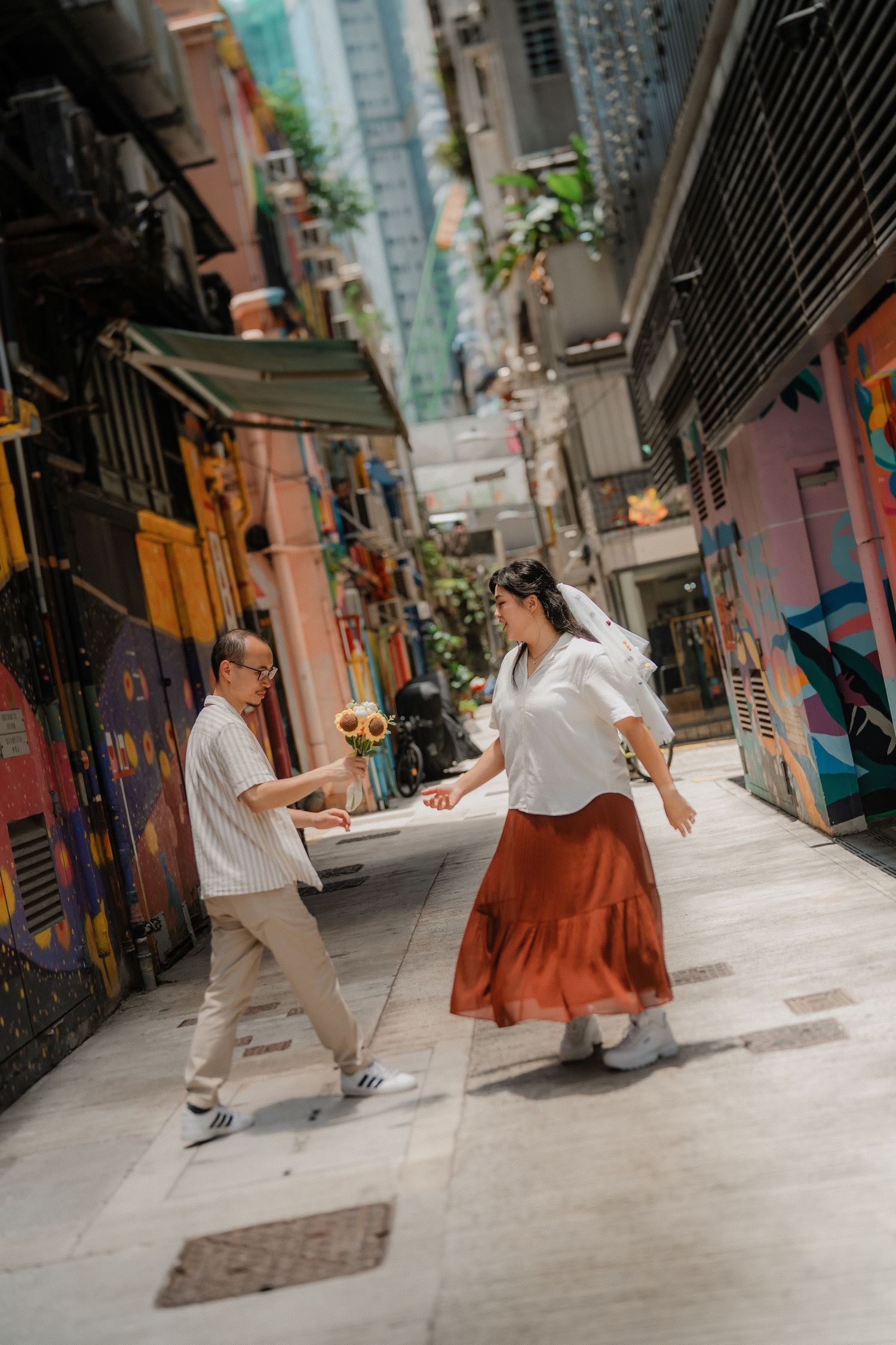 A couple dances together in a narrow alley with vibrant painted walls and urban architecture.