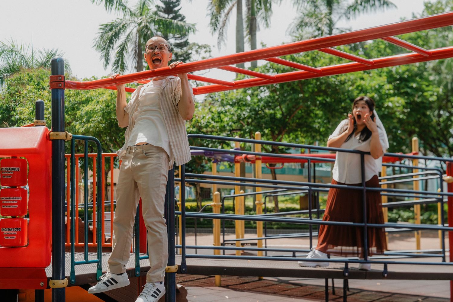 Athletes train on parallel bars in an outdoor fitness area surrounded by palm trees and tropical vegetation.
