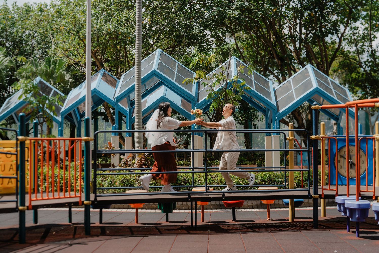 A scenic row of colorful beachfront cabanas with pointed roofs line up along a boardwalk under green trees.