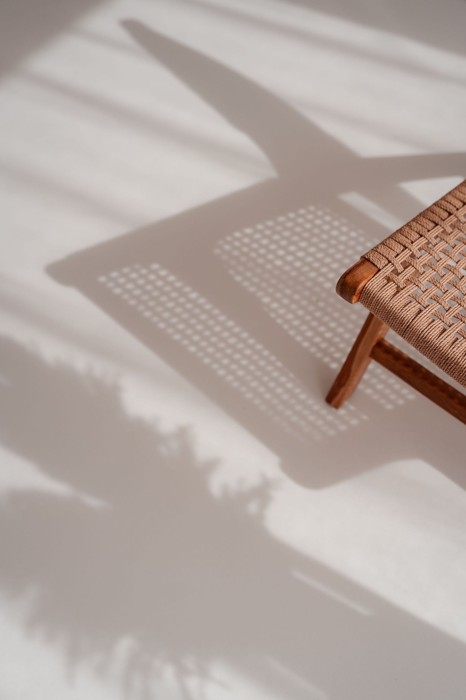 Holzstuhl wirft im Sonnenlicht einen weichen Schatten auf den Boden, minimalistische Studiostimmung