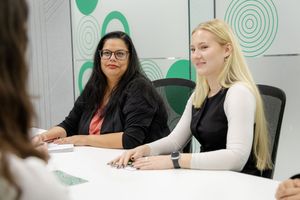 People sitting at a conference table having a business meeting in a modern office space with green wall accents.