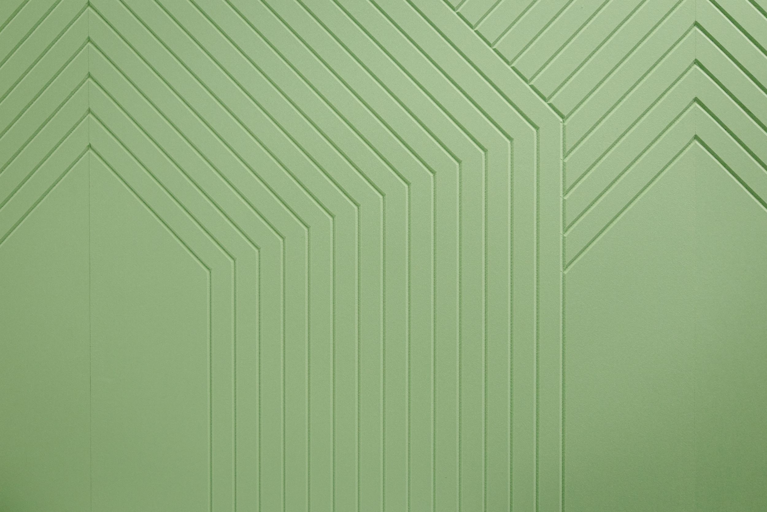 Modern light green geometric wall pattern with diagonal stripes and angular design creating a herringbone texture.