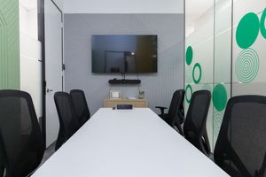 Modern office space interior with white walls, green circle designs, and mounted TV screens on the walls.