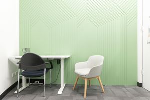 Minimalist office interior with green chevron wall pattern and contemporary white chairs.