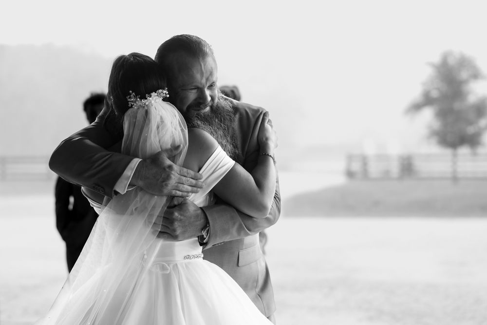 A tender moment between newlyweds embracing outdoors, captured in black and white photography.