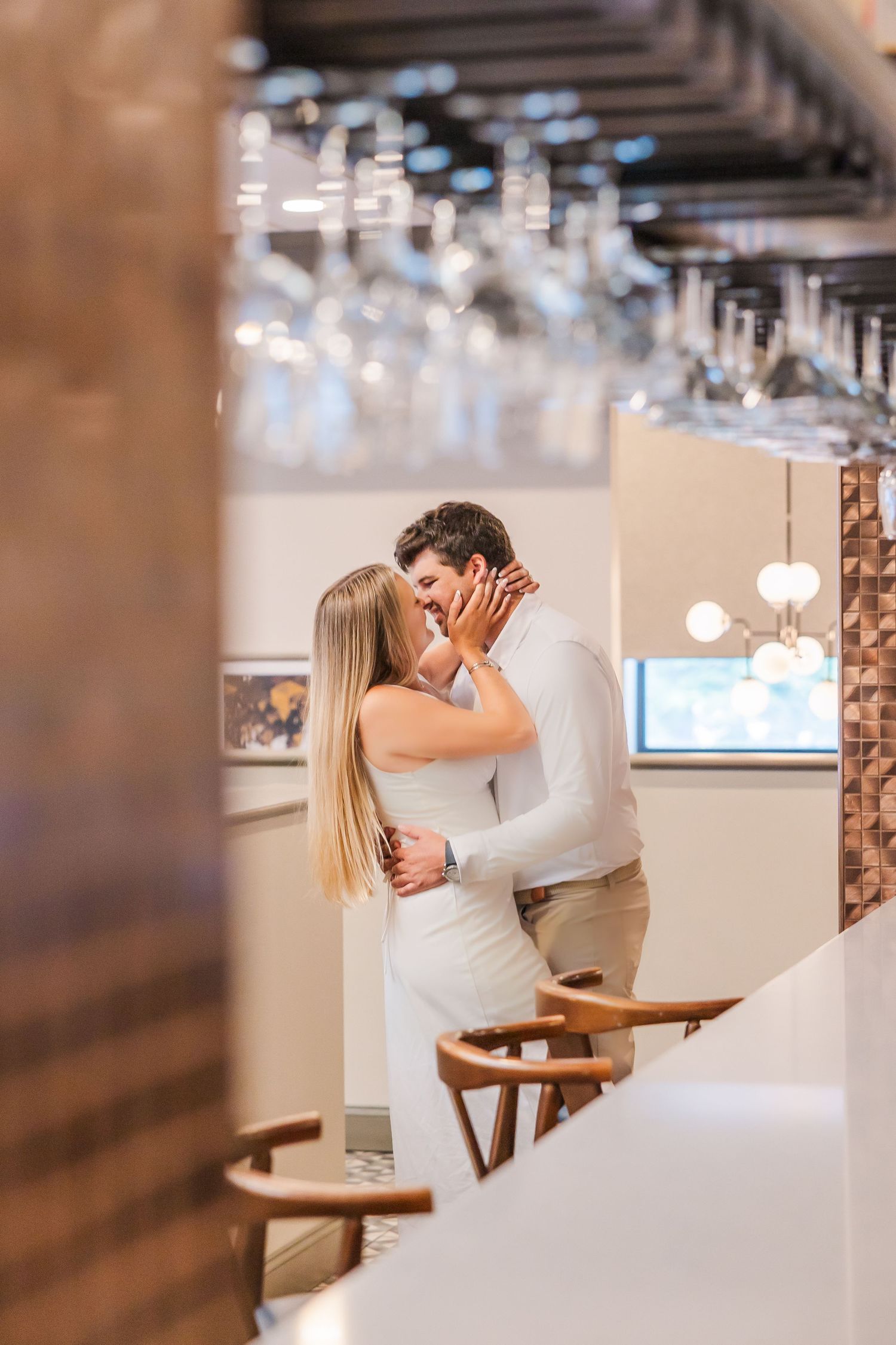 A romantic proposal moment captured in a modern restaurant setting showing two people embracing after the proposal.
