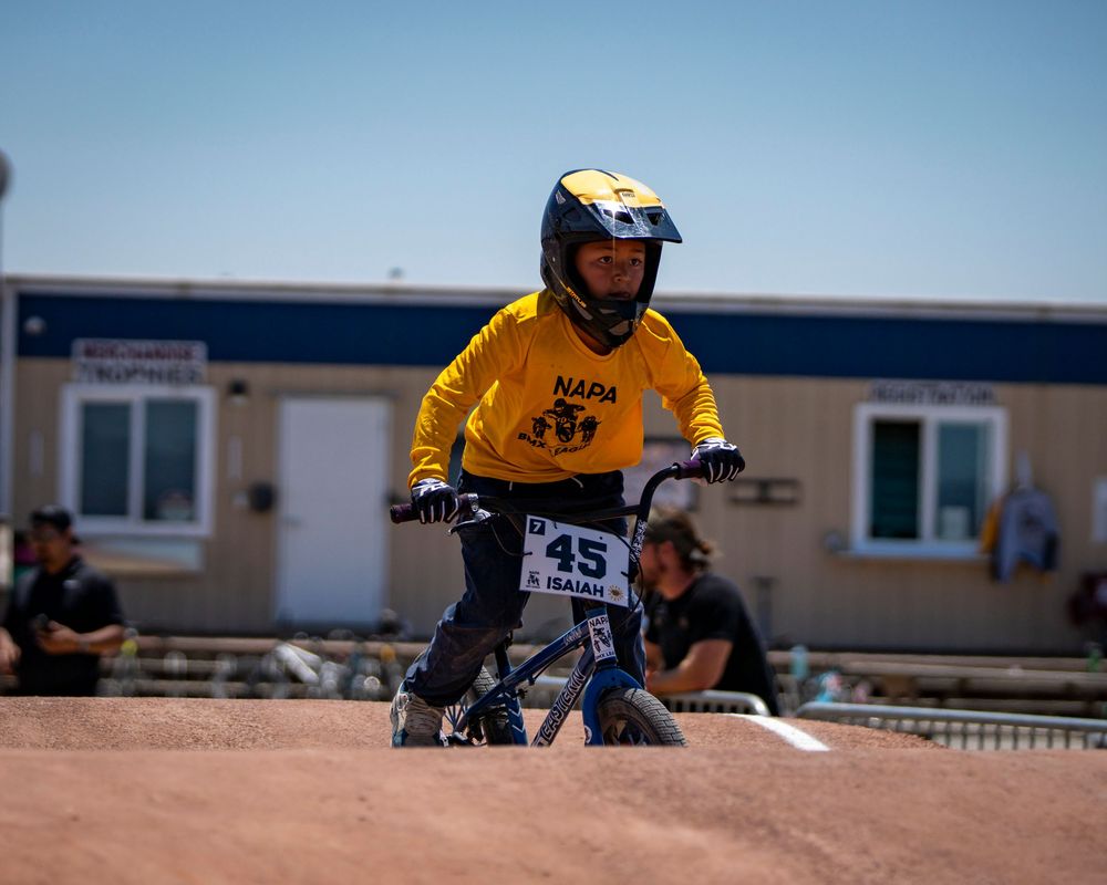 BMX athlete in yellow jersey navigates race course during competition.
