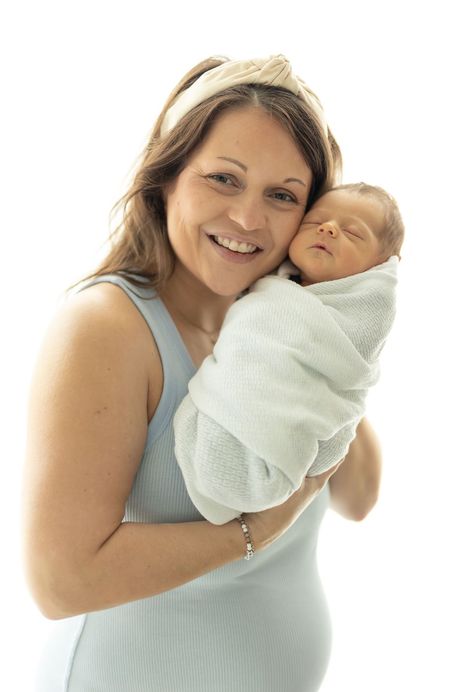 Mother and newborn baby nuzzled together against a simple white backdrop
