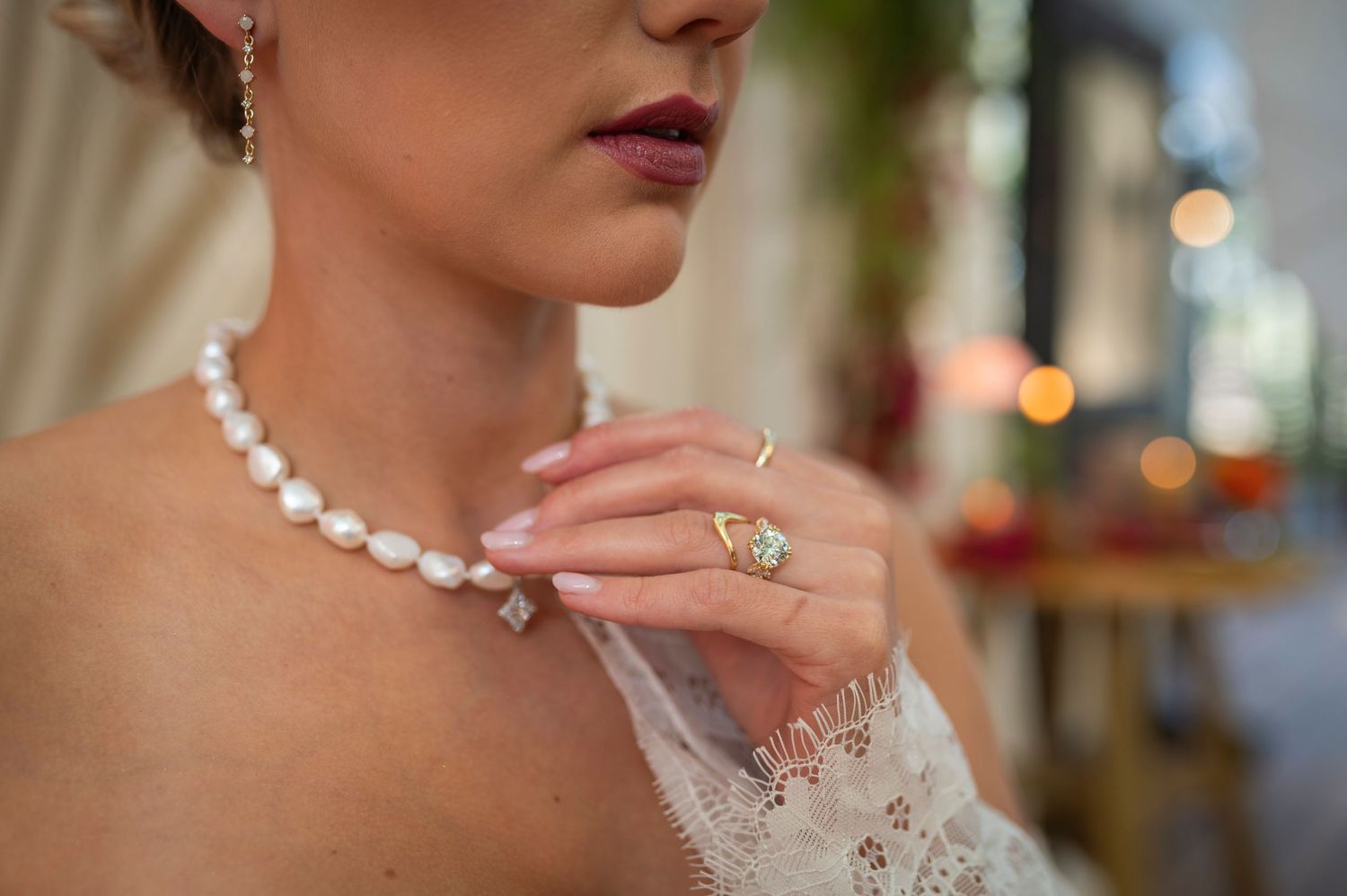 A close-up detail shot shows a delicate white pearl necklace with a shimmering clasp against formal attire.