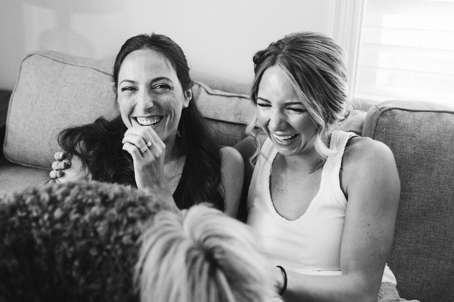 Candid black and white photo of friends sharing a laugh on a couch.