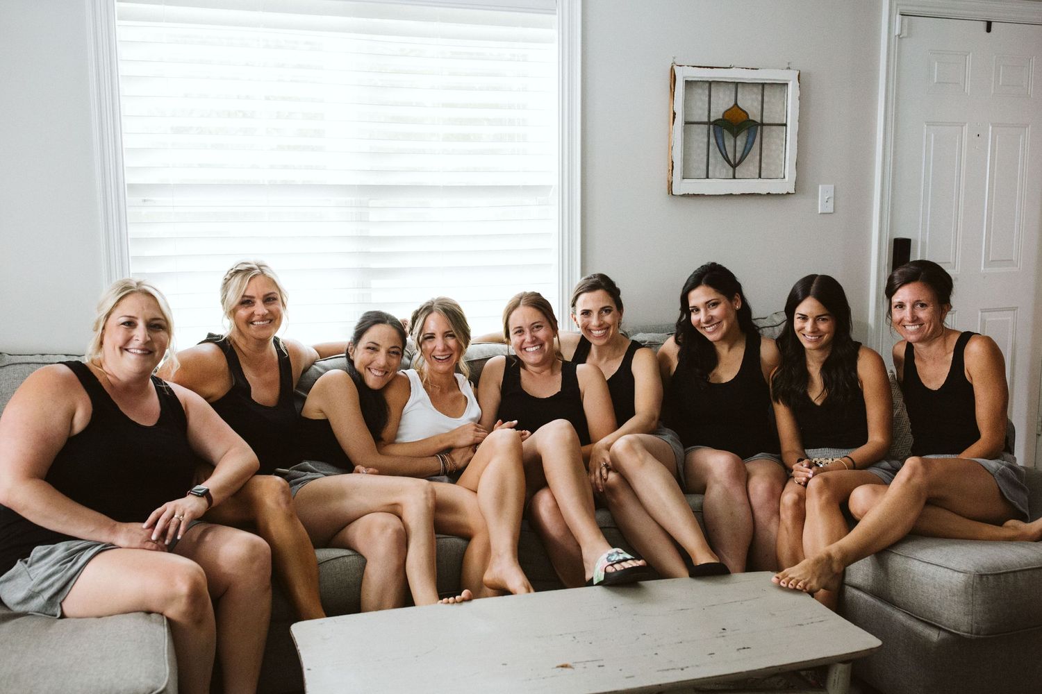 Group of friends in black and white outfits gathered on a gray sectional sofa.