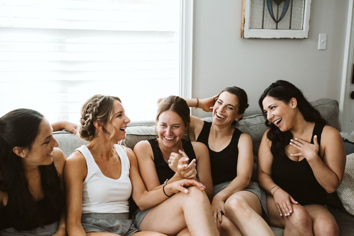Casual gathering of friends on a couch with a small dog joining the fun.