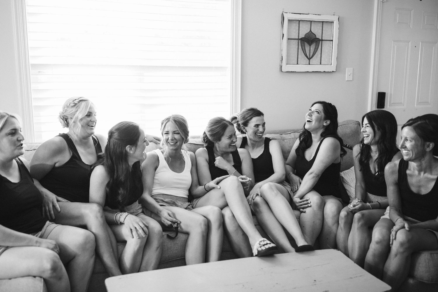 Black and white photo of a group sharing laughter during a casual indoor gathering.