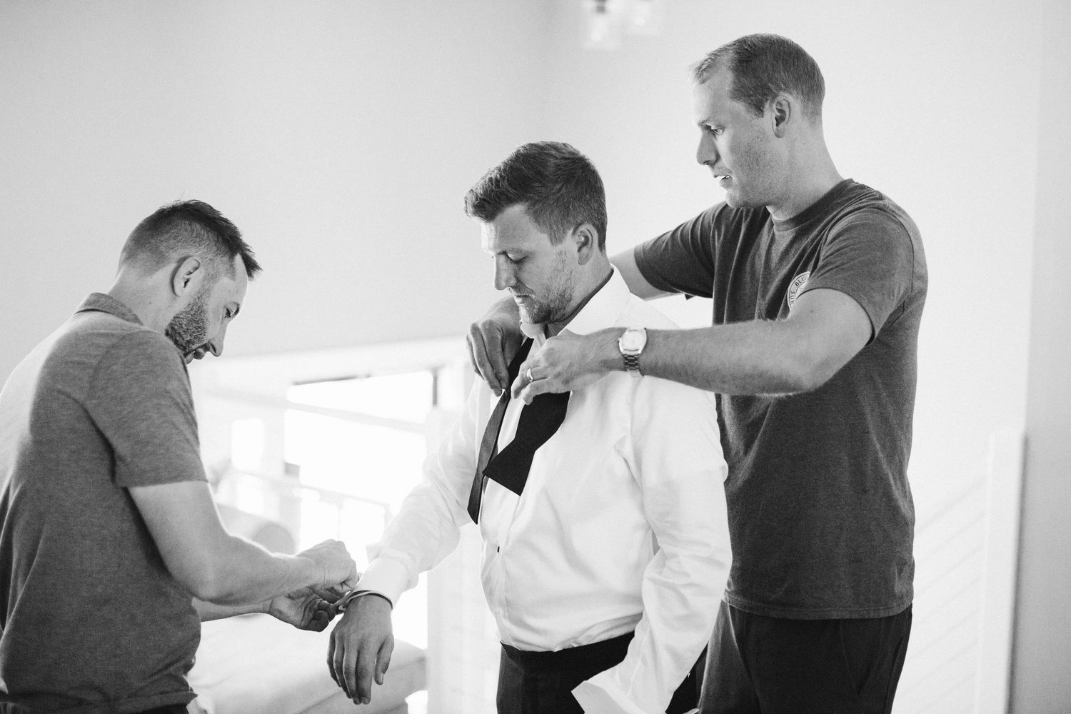 Groomsmen sharing laughs and embracing during wedding preparations.