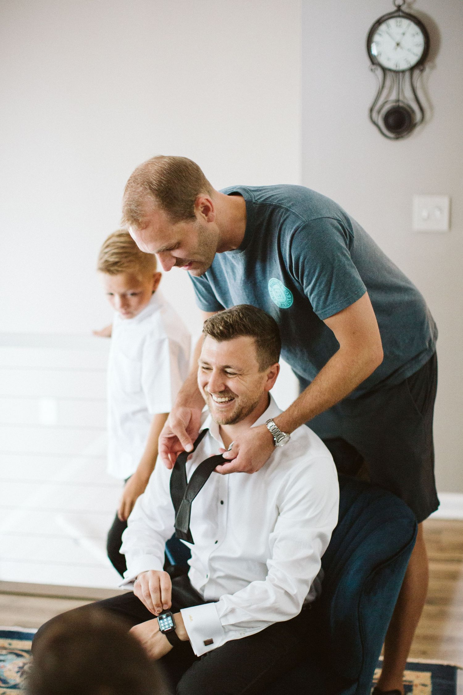 Candid moment of laughter and camaraderie between groomsmen in formal attire.