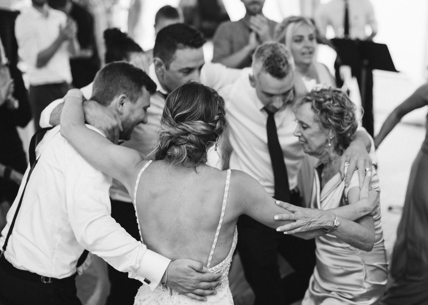 Black and white photo of wedding guests dancing together at a lively reception.