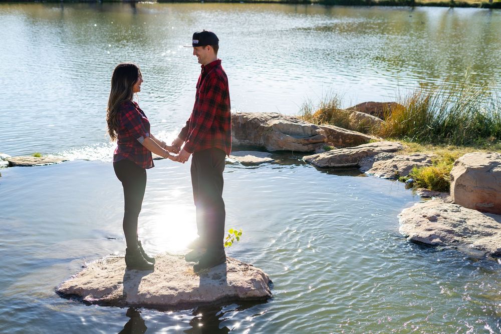 Two people stand together near a tranquil lake surrounded by rocks and greenery.  alt="Professional photography in Lubbock TX by H & Co. Cre