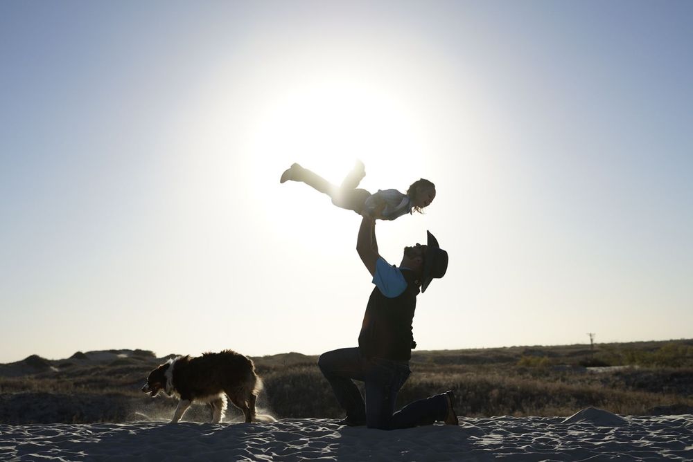 Silhouettes playfully posing and jumping against a bright sunset sky. alt="Professional photography in Lubbock TX by H & Co. Creative