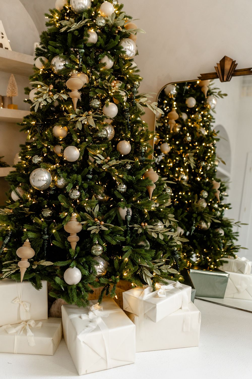A luxurious Christmas tree decorated with white and gold ornaments set in an elegant white box base.