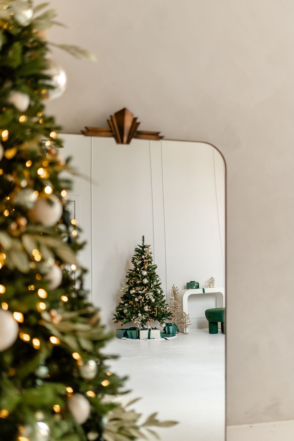 White living room decorated for Christmas with modern minimalist holiday decor and a decorated tree in the corner.