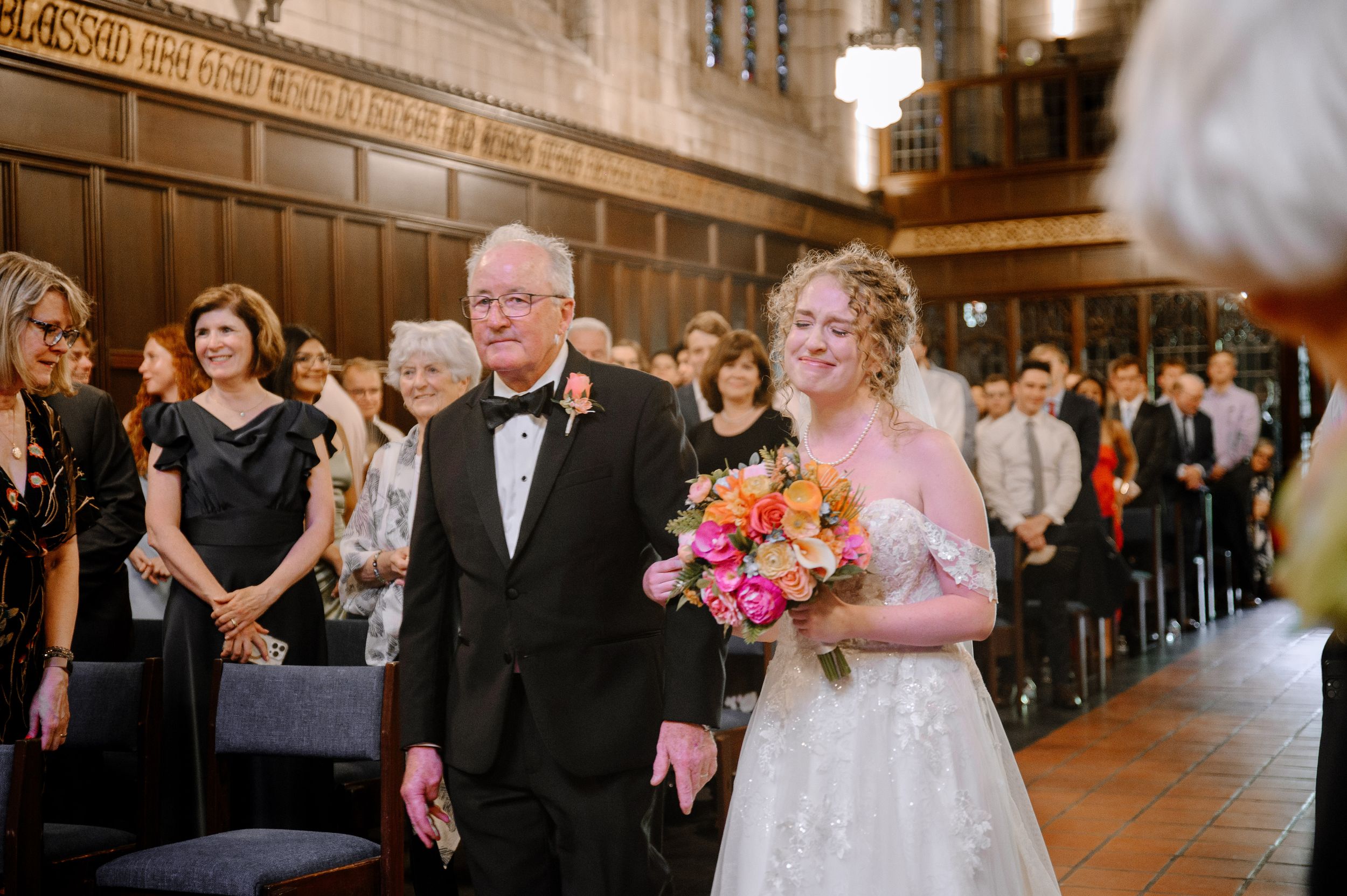 A joyful wedding ceremony taking place in an elegant church chapel with wood paneling and pews filled with guests.