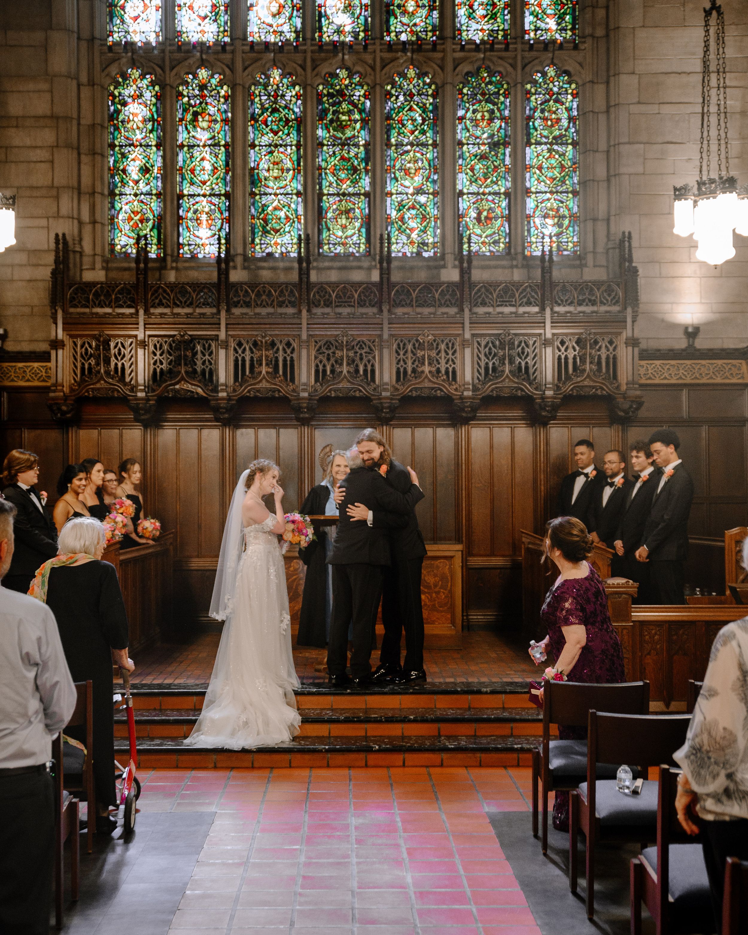 Wedding ceremony taking place in a traditional church sanctuary with stained glass windows and wooden pews.