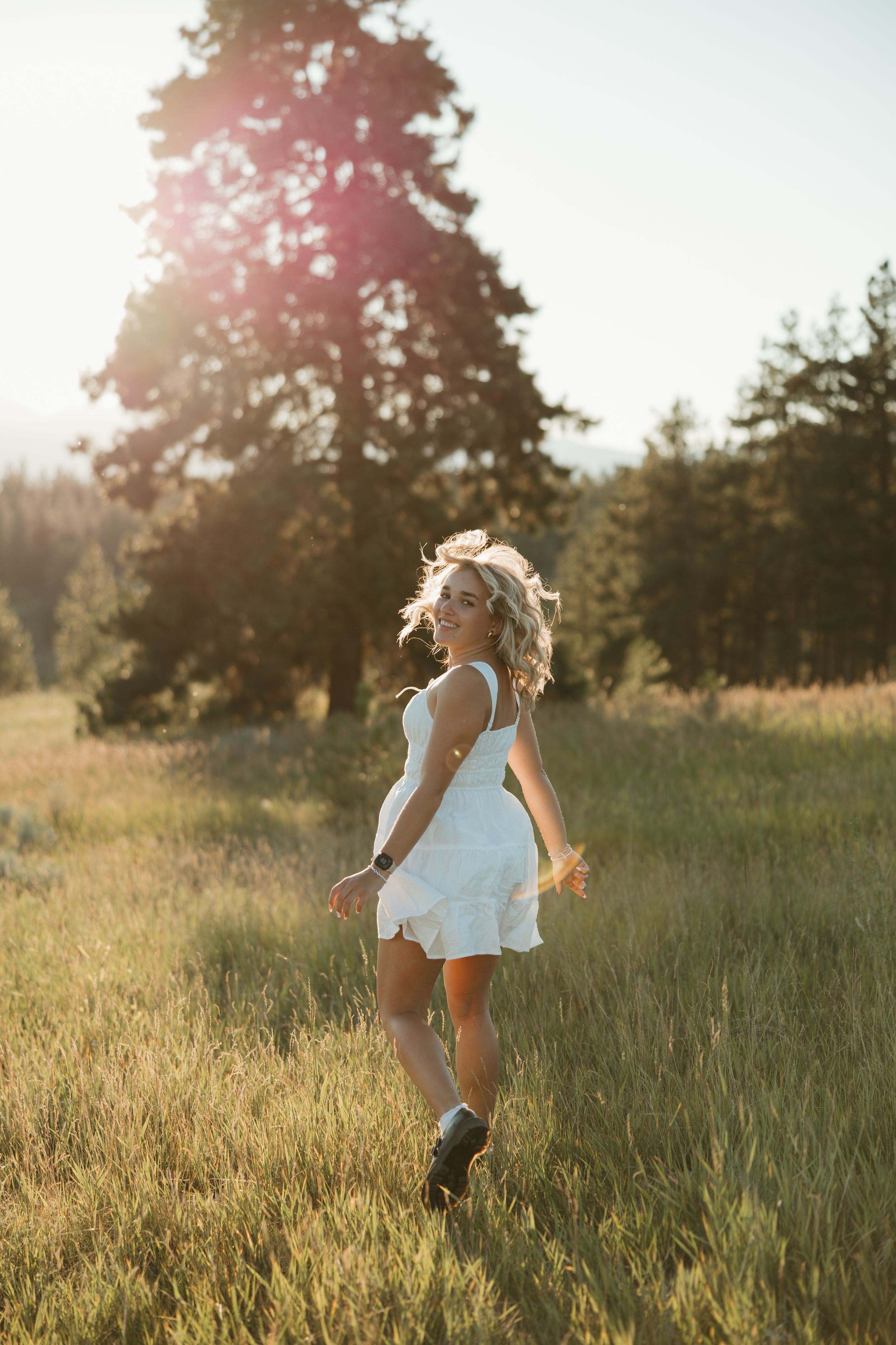 Golden hour sunlight illuminates long grass while a white dress flows gracefully in a serene meadow setting.