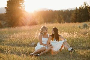 Two people sitting in a golden sunlit meadow at sunset while having an intimate conversation.