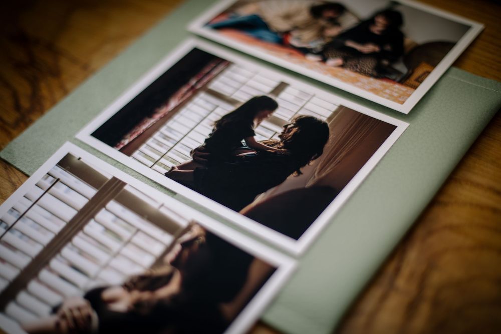 Three polaroid style photographs arranged on a mint green surface showing intimate monochrome portrait moments.