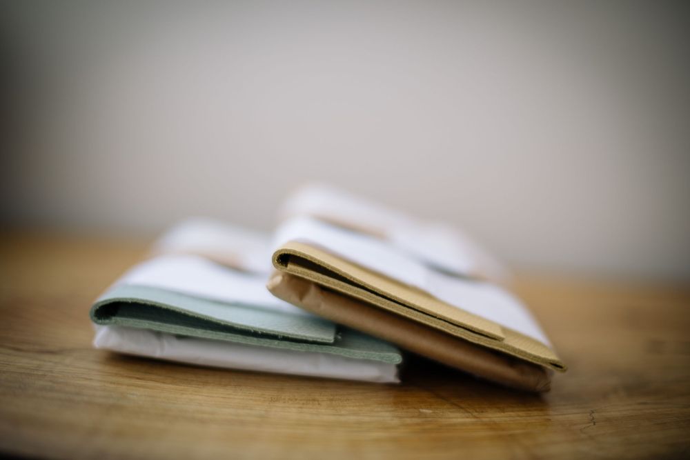 Three stacked notebooks with bent pages lying on a wooden surface in soft focus.