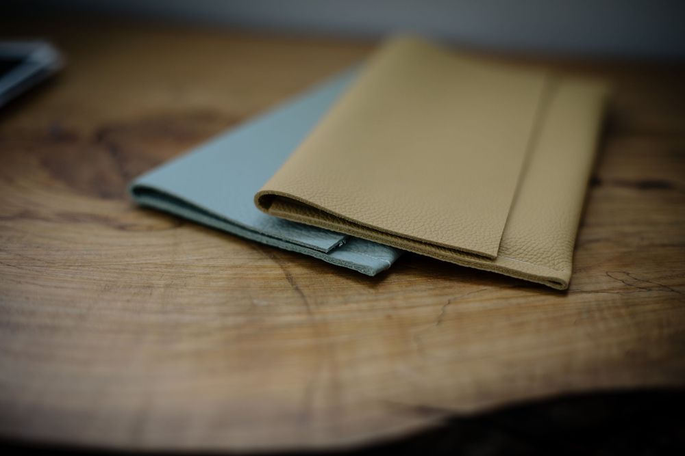 Minimalist composition of notebooks with light blue and beige covers on a rustic wooden surface.