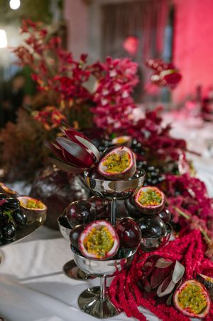 Passion fruit and grapes arranged with vibrant pink florals create an elegant party table display.