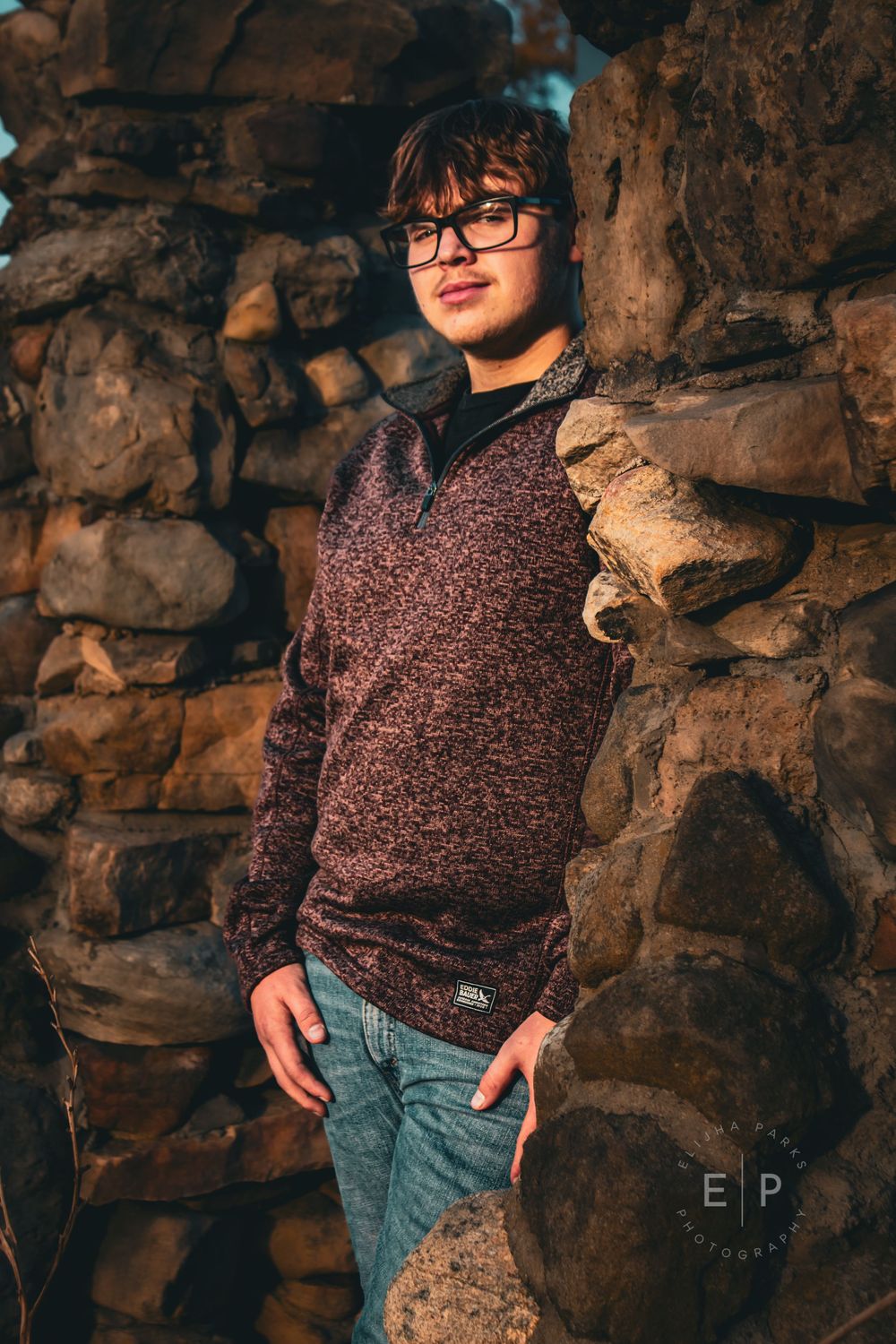 Senior boy posing between stone walls.