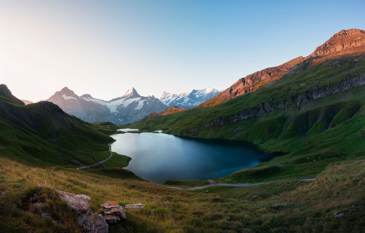 Alpine lake surrounded by mountain peaks during sunset in a pristine wilderness setting.