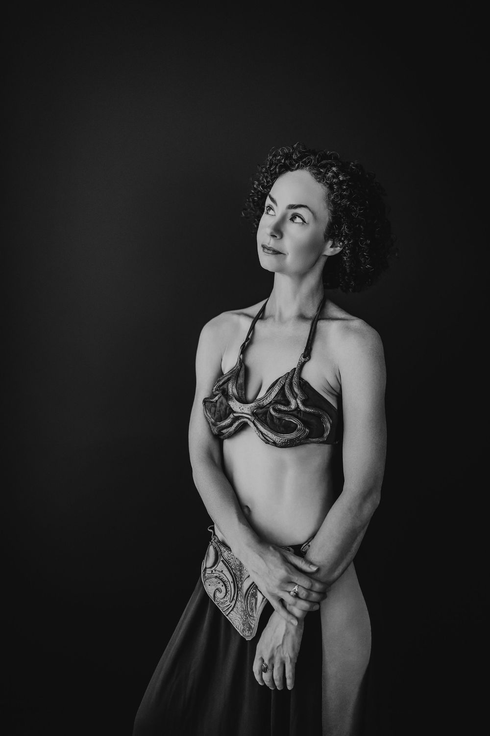 A dark and moody black and white boudoir photo series showcasing dramatic poses against a black background.