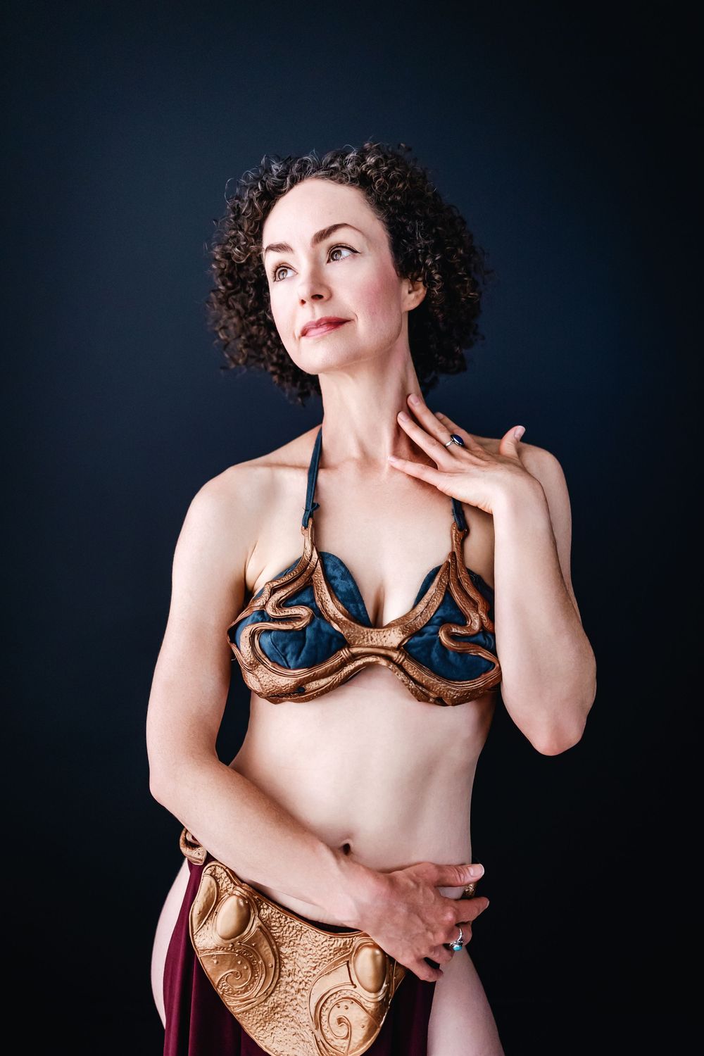 Portrait against dark background showing performer in elaborately decorated blue and gold dance costume.